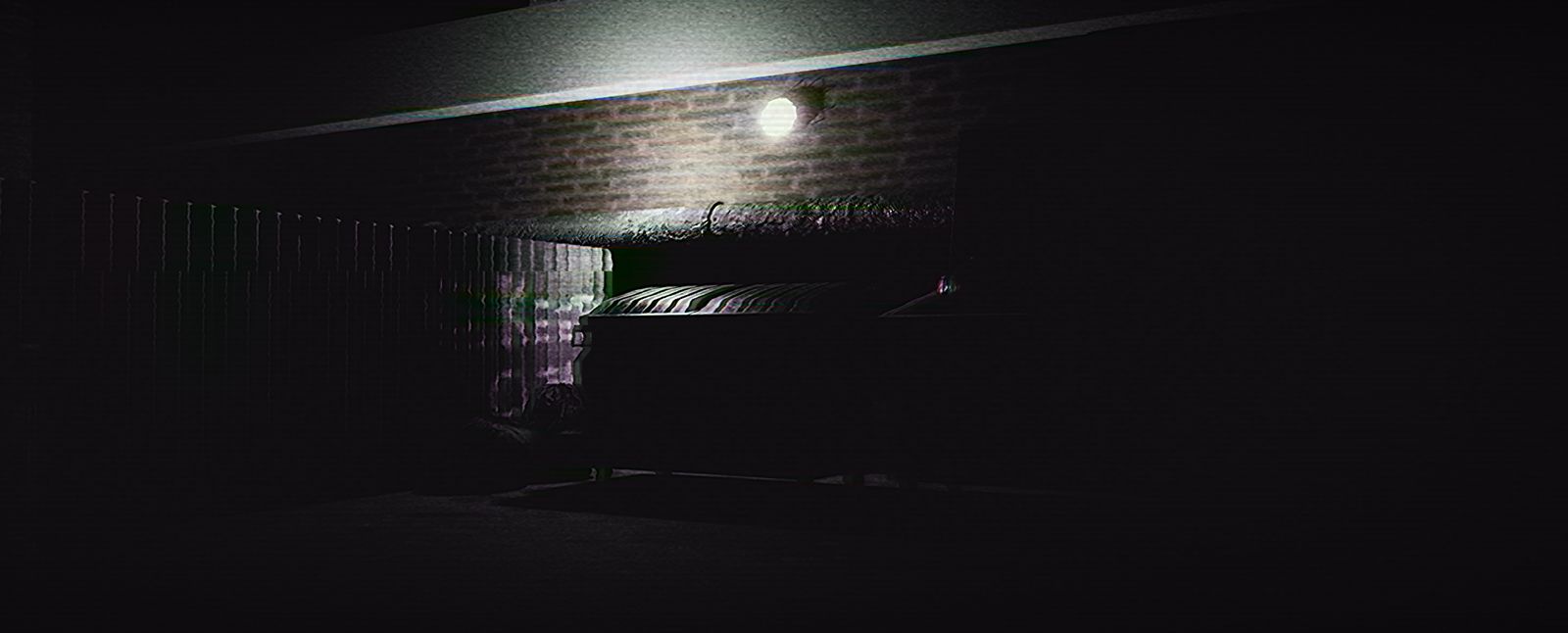 A dumpster in the service alley under a single wall light
