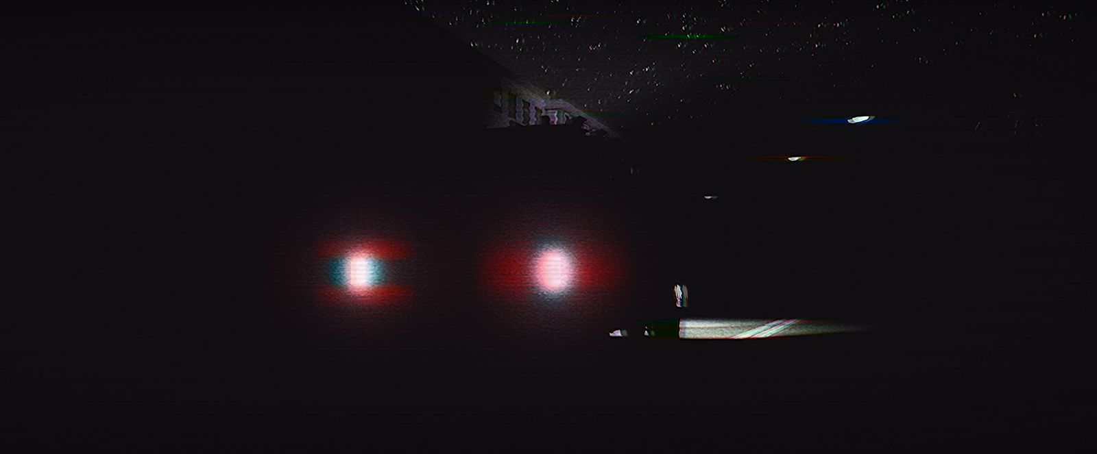 Two headlights burning in near-total darkness